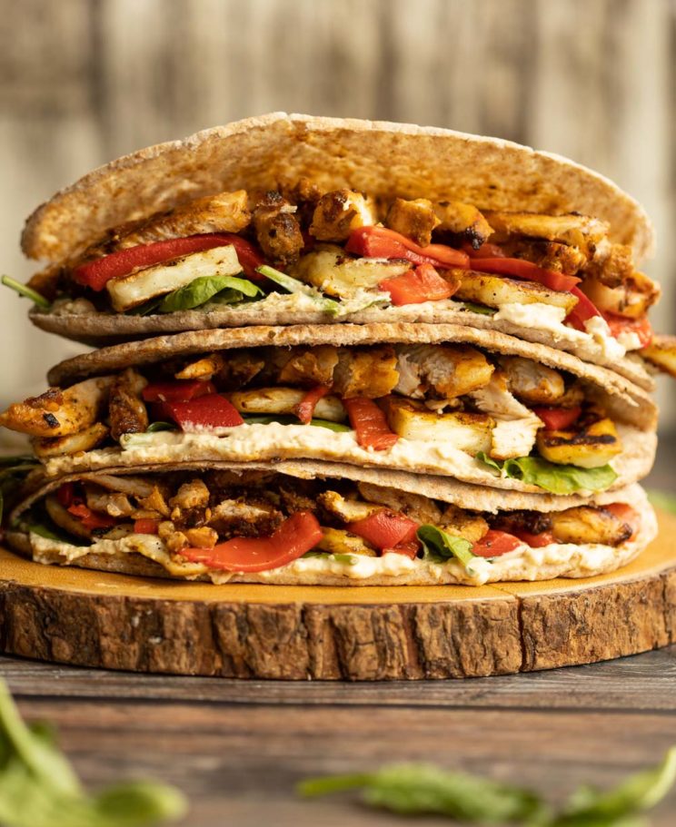 pitas stacked on each other on wooden board garnished with spinach leaves