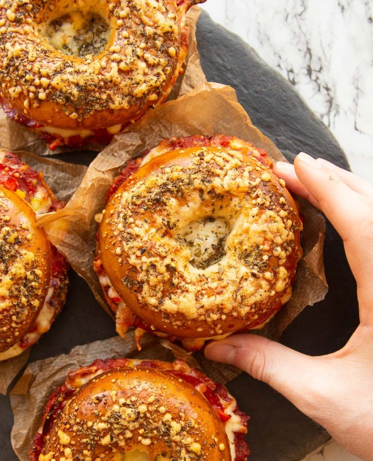 overhead shot of bagels on slate with hand grabbing one