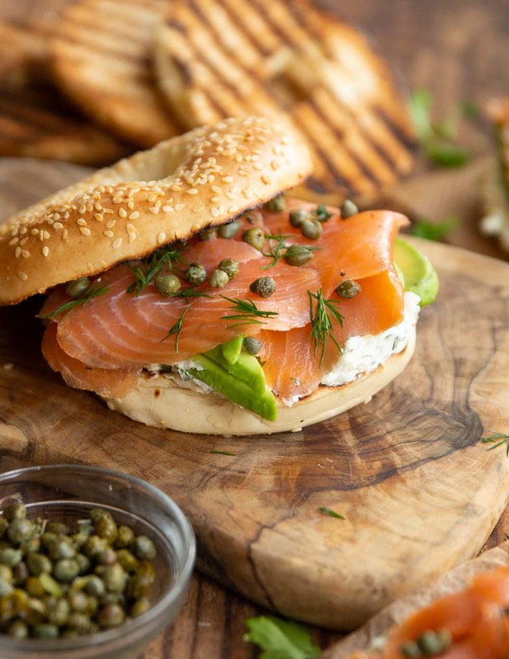 open top bagel surrounded by ingredients and more bagels blurred in the background