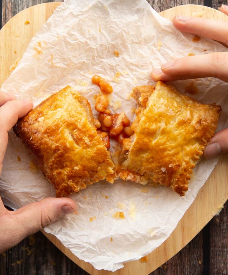 overhead shot of two hands splitting open slice on parchment paper
