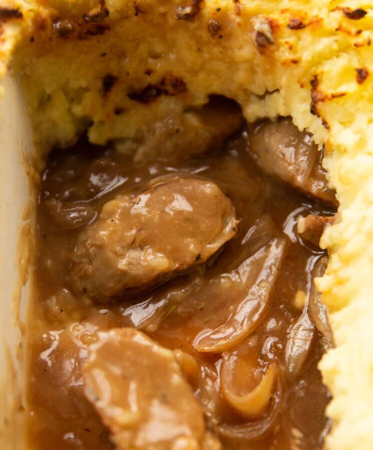 close up shot of sausage and mashed potato pie showing filling in baking dish