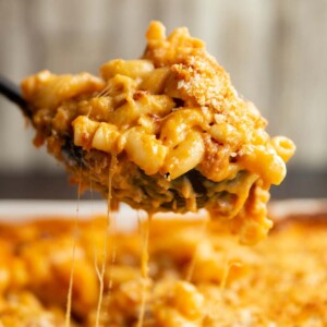 serving spoon with mac and cheese in it dripping down into dish