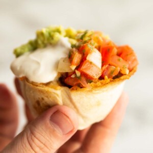 hand holding tortilla cup above white background
