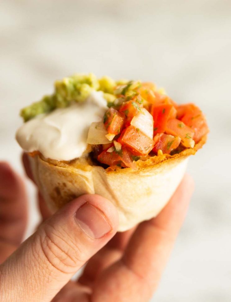 hand holding tortilla cup above white background
