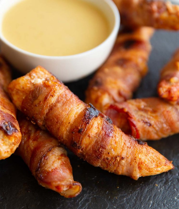 closeup shot of chicken tender resting on small white pot of dipping sauce