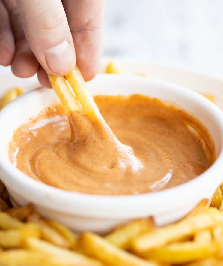 hand dunking french fries into bbq mayo 