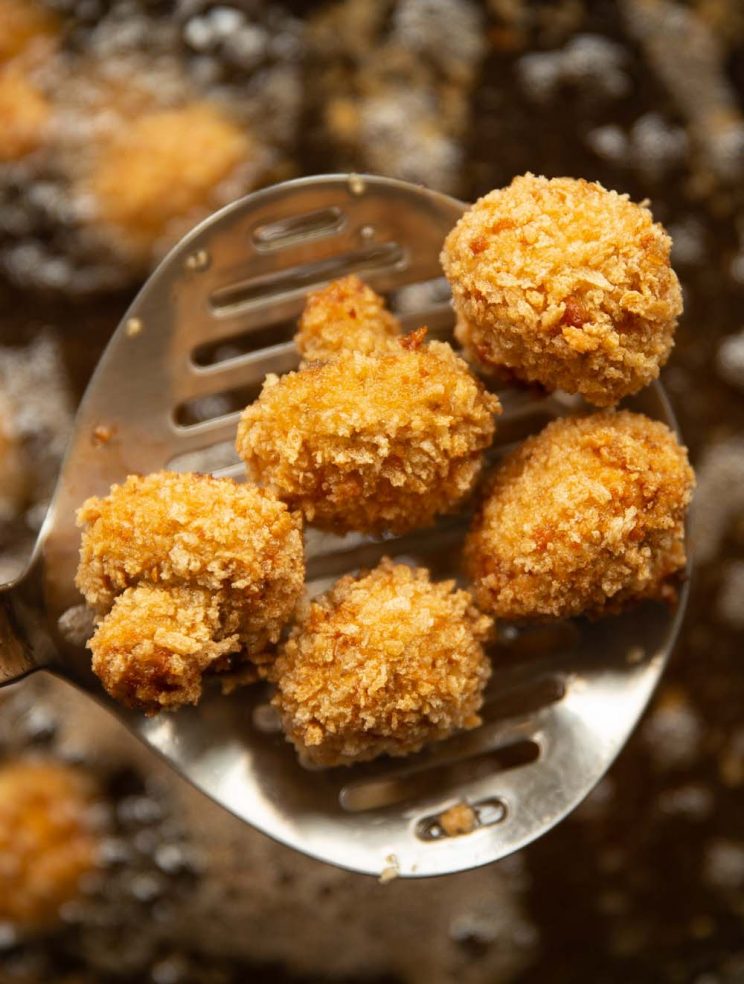 overhead shot of mushrooms scooped out of hot oil with slotted spoon