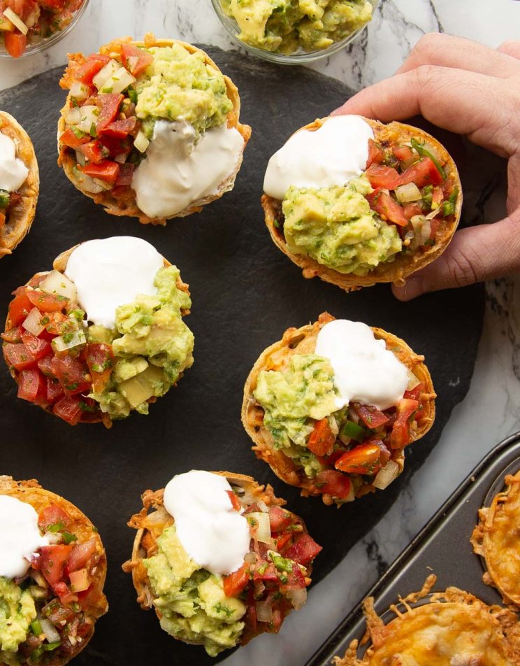 overhead shot of burritos across marble background with hand grabbing one