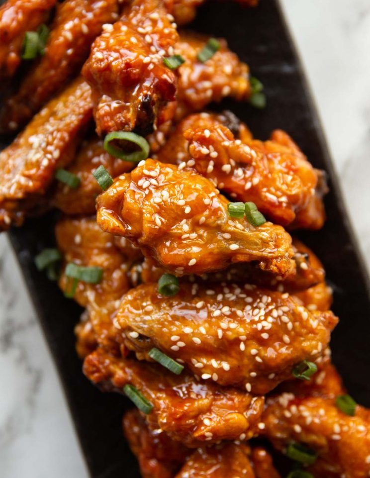 overhead shot of chicken wings stacked on rectangular slate plate