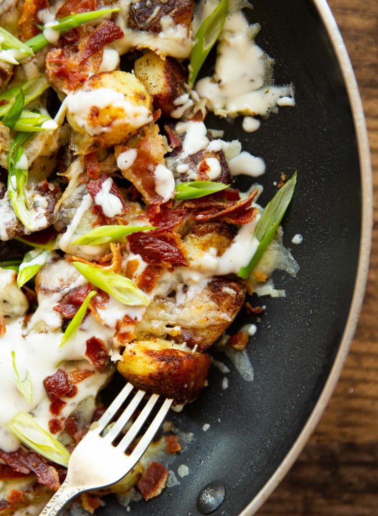 overhead shot of fork digging into potatoes in skillet