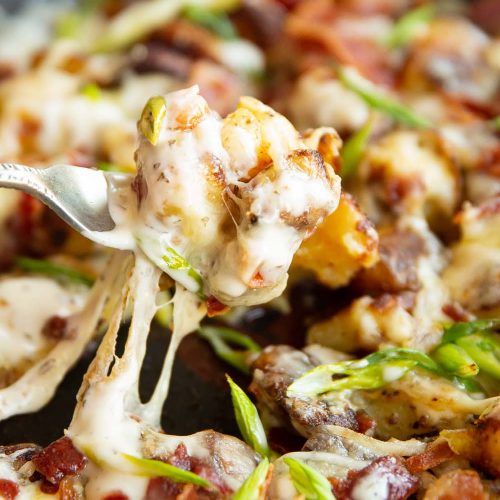 fork lifting potato out of pan with cheese dripping down