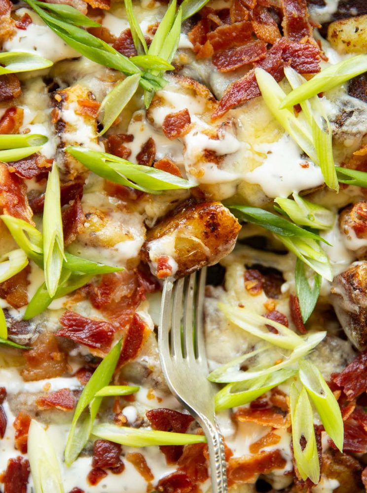 overhead shot of fork stabbing potato coated in ranch