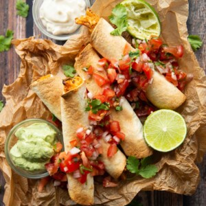 overhead shot of 4 taquitos served with salsa and avocado dip