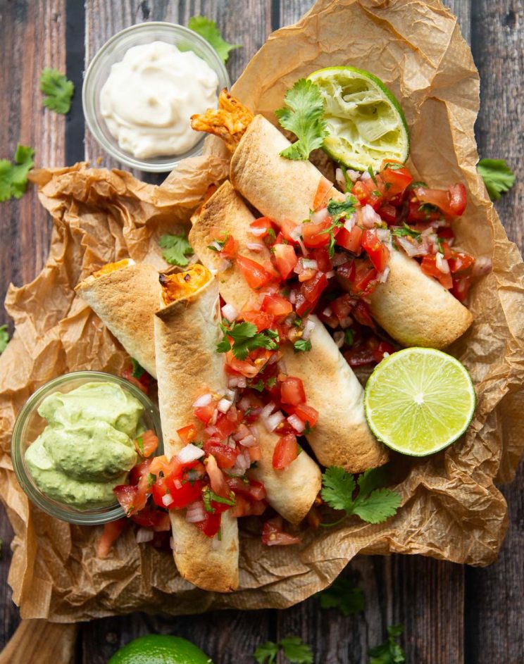 overhead shot of 4 taquitos served with salsa and avocado dip