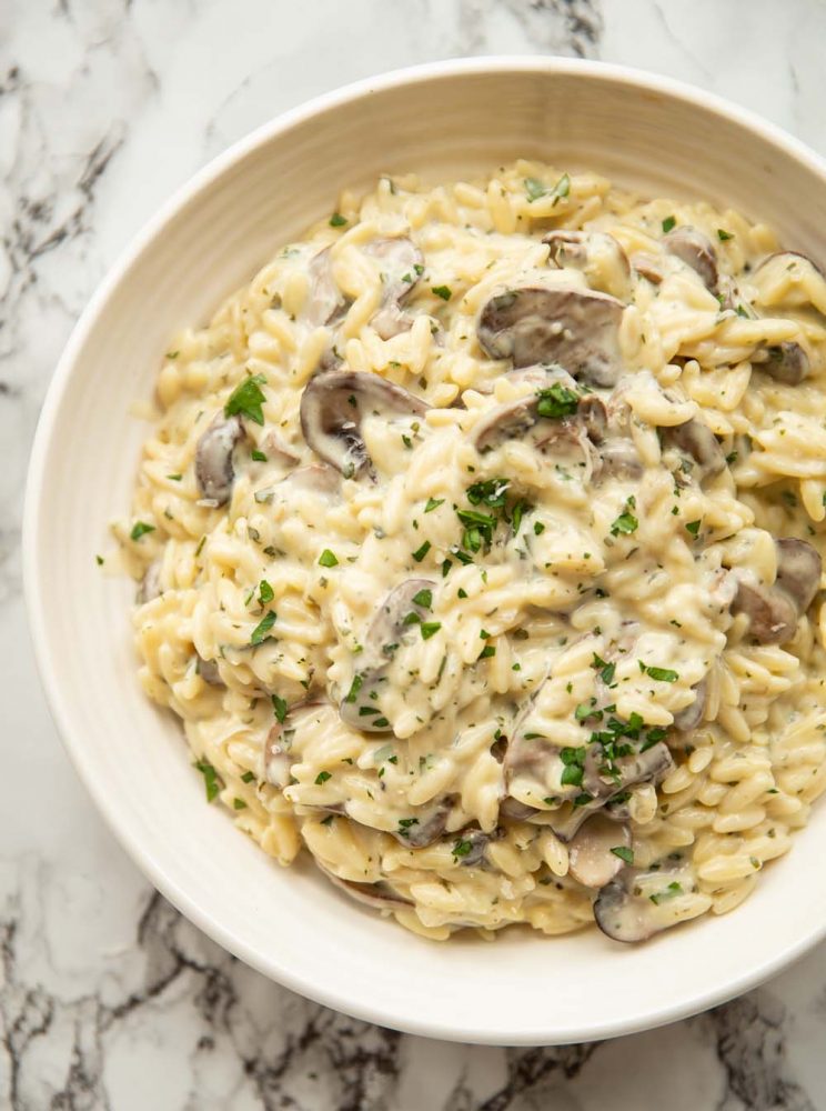 overhead shot of orzo in white bowl on marble background