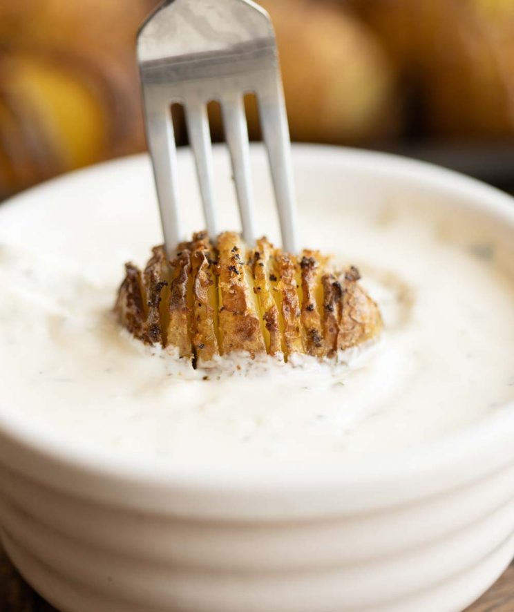 fork with potato dunking into pot of creamy dip