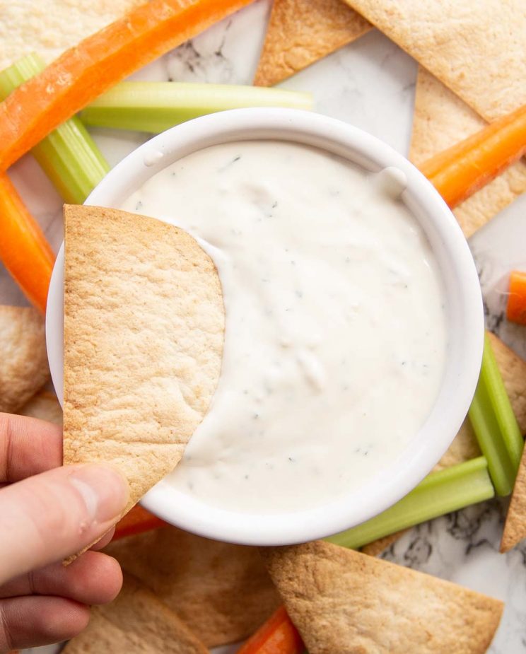 overhead shot of dunking tortilla chip into dip