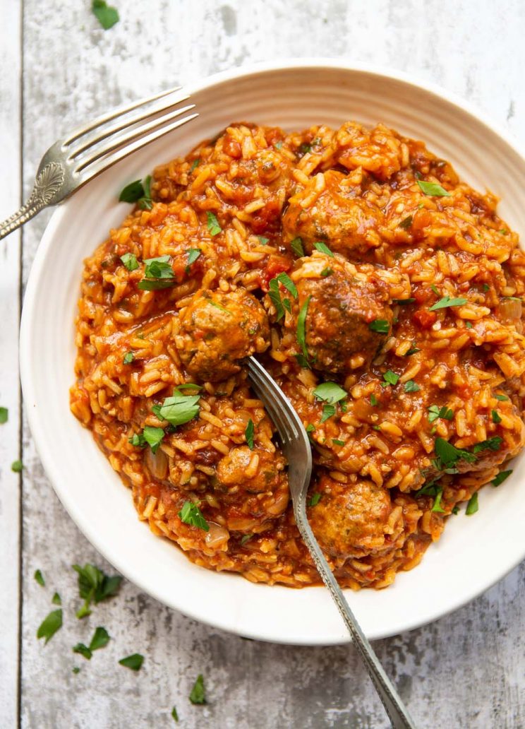 overhead shot of meatballs and rice in white bowl garnished with parsley