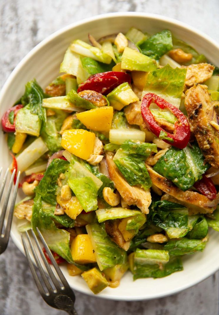 overhead shot of salad in white bowl with two silver forks resting on side