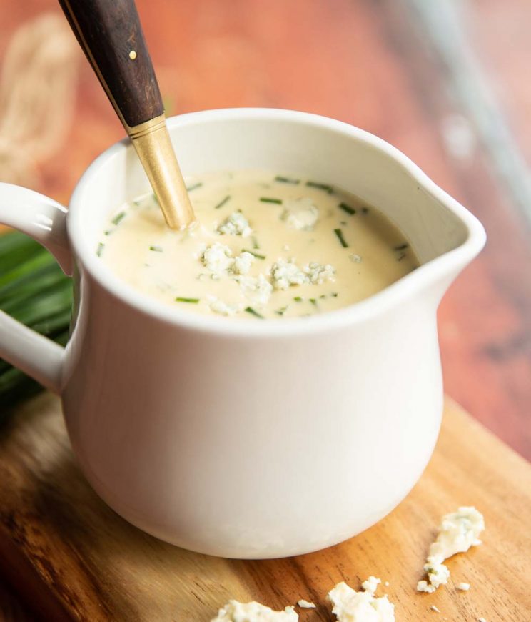 closeup shot of sauce in small white jug with golden spoon inside