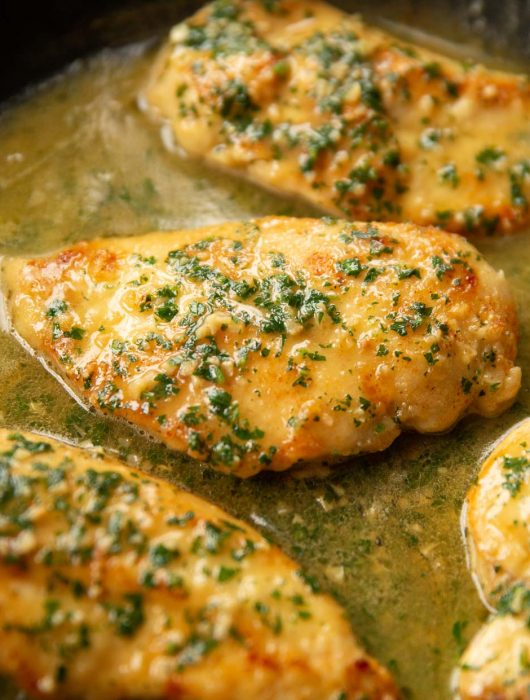 close up shot of chicken in skillet garnished with parsley