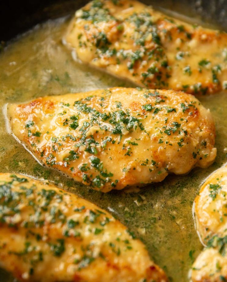 close up shot of chicken in skillet garnished with parsley