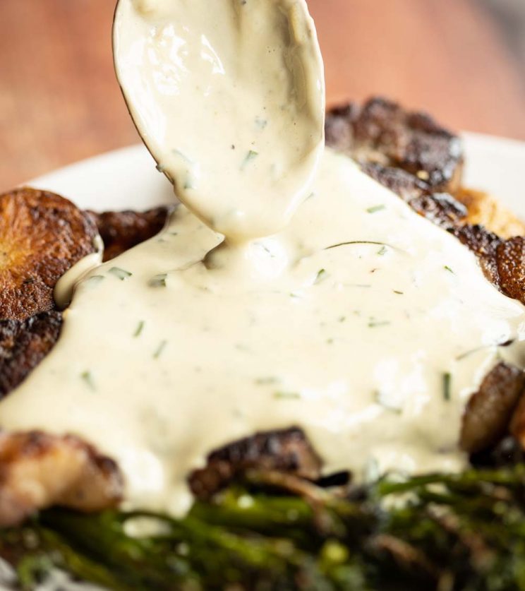 closeup shot of spoon pouring blue cheese sauce over steak