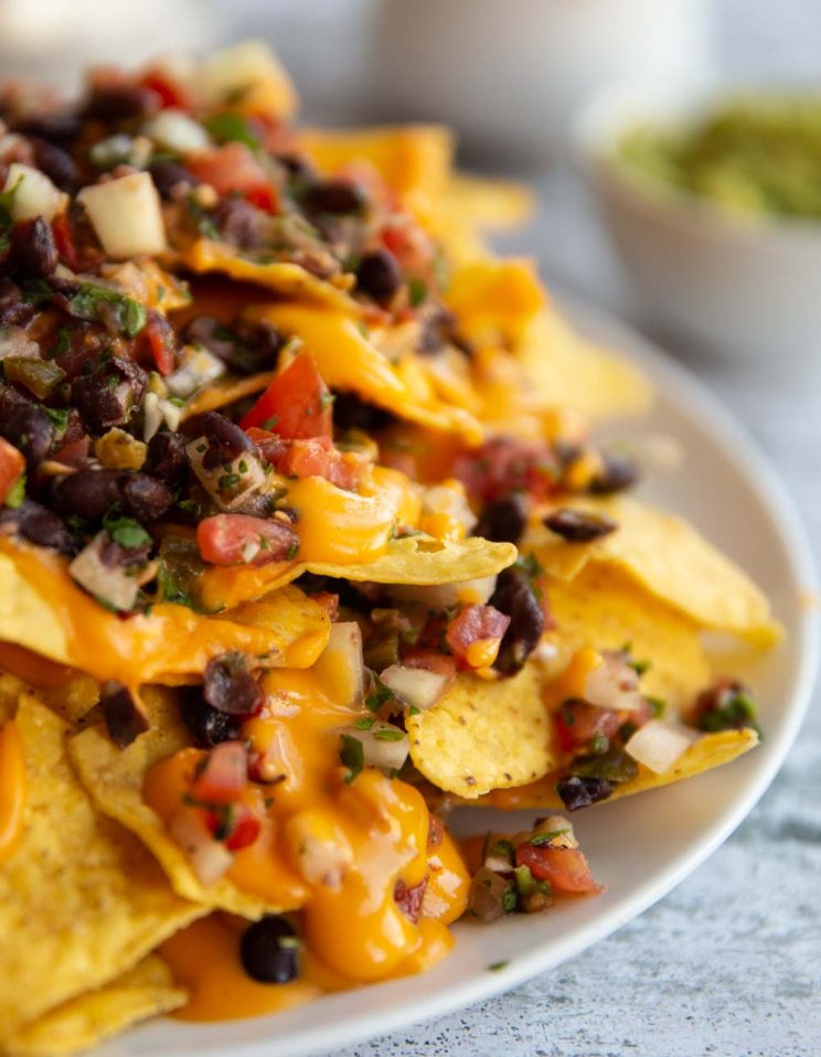 side view of double layer nachos with guac blurred in background