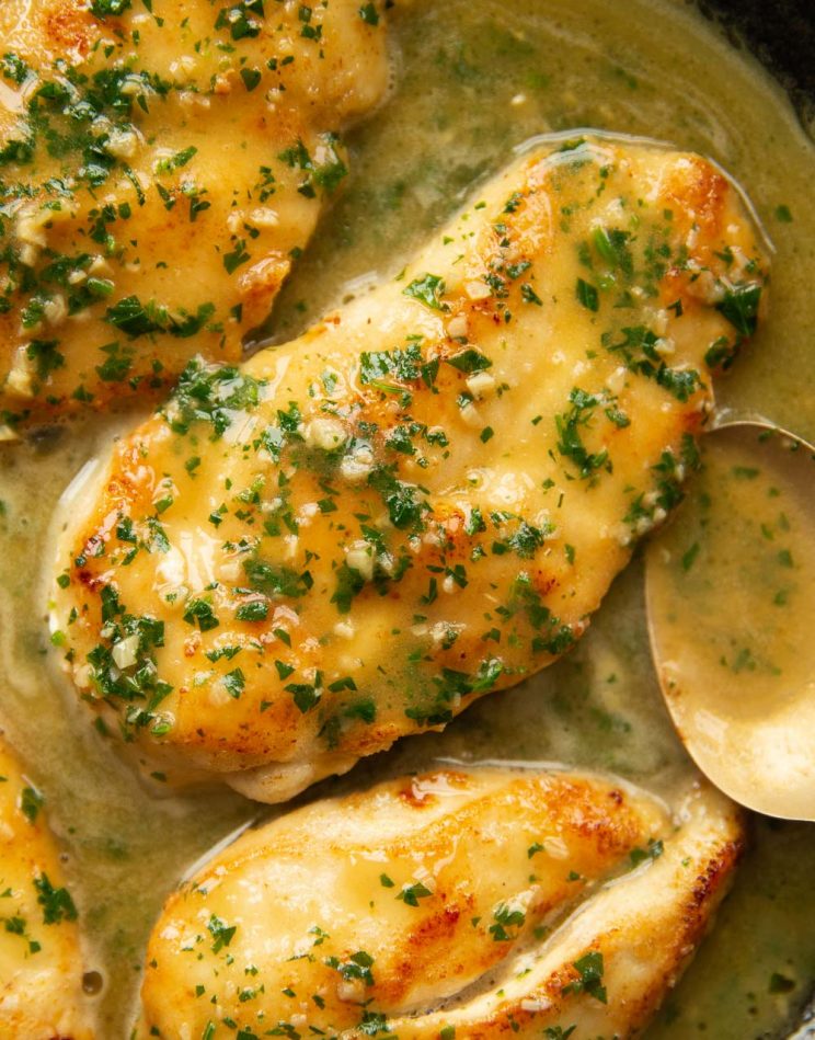 close up overhead shot of chicken in pan with golden spoon next to it