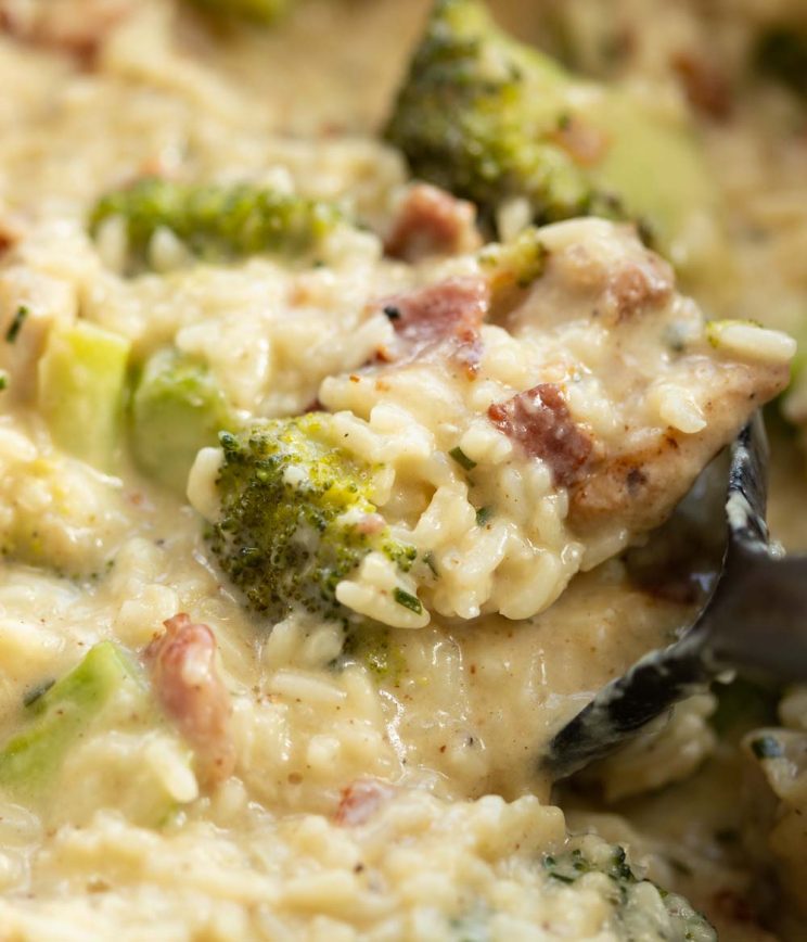 close up shot of serving spoon digging into rice in casserole dish