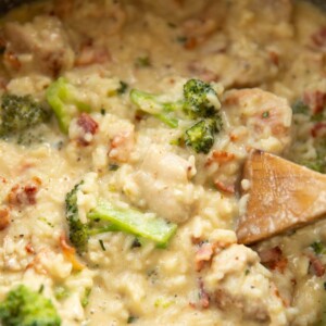 over head shot of chicken broccoli rice in casserole dish with wooden spoon diving in