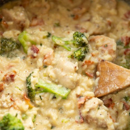 over head shot of chicken broccoli rice in casserole dish with wooden spoon diving in