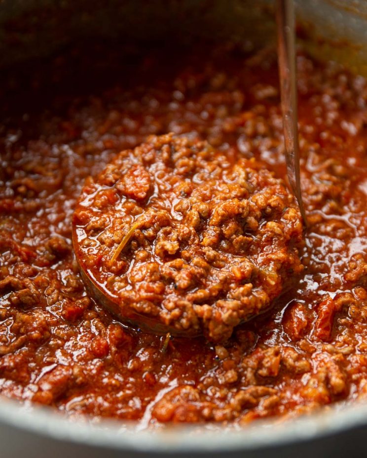 close up shot of ladle in pot scooping out bolognese