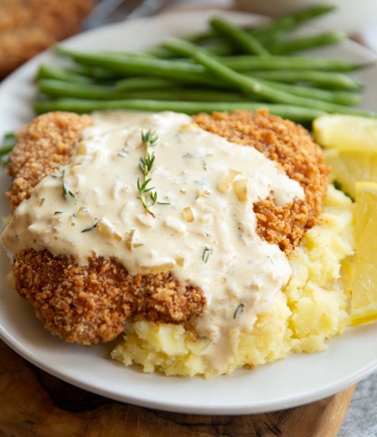 close up shot of sauce dripping down schnitzel onto mashed potato