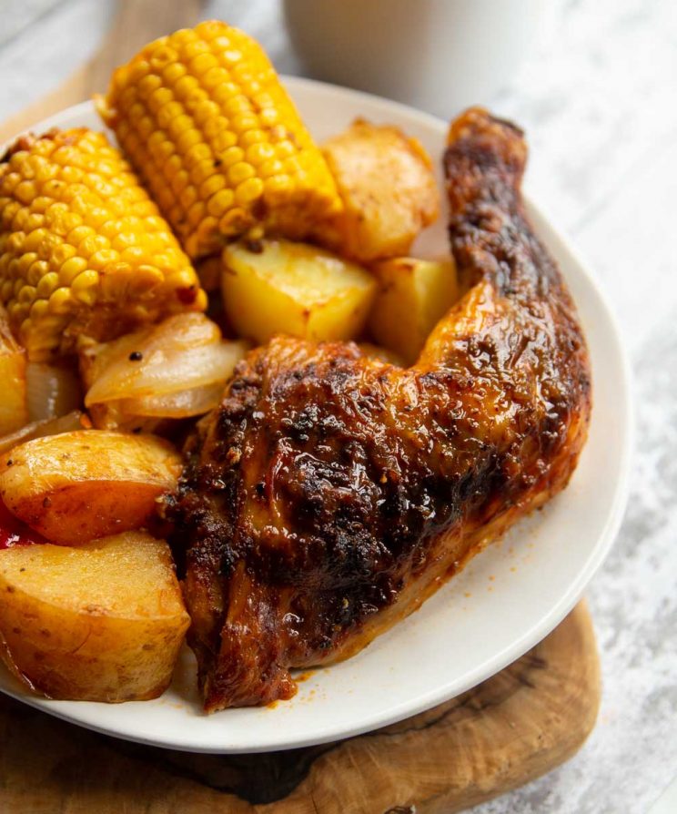 closeup shot of chicken leg on white plate with veg