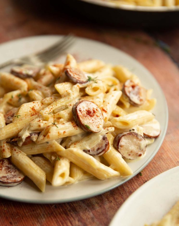 side shot of pasta on white plate garnished with pinches of smoked paprika