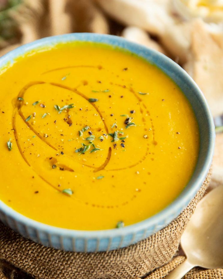 carrot soup in small blue bowl wrapped in brown cloth