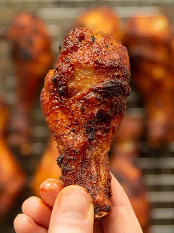 overhead shot of holding chicken drumstick close to camera with more blurred in background