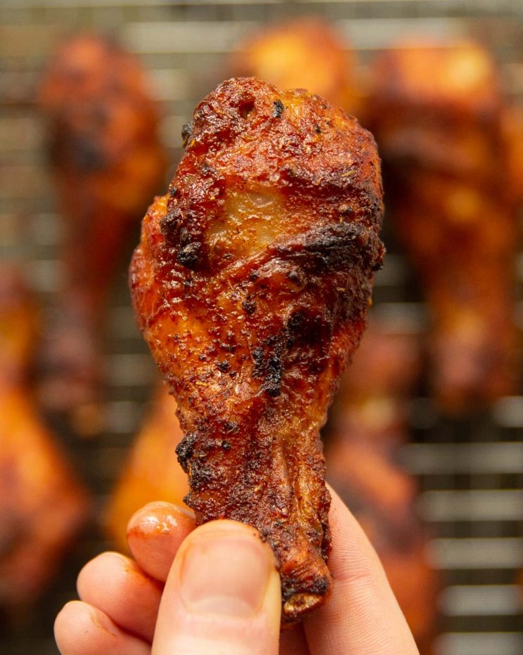 overhead shot of holding chicken drumstick close to camera with more blurred in background