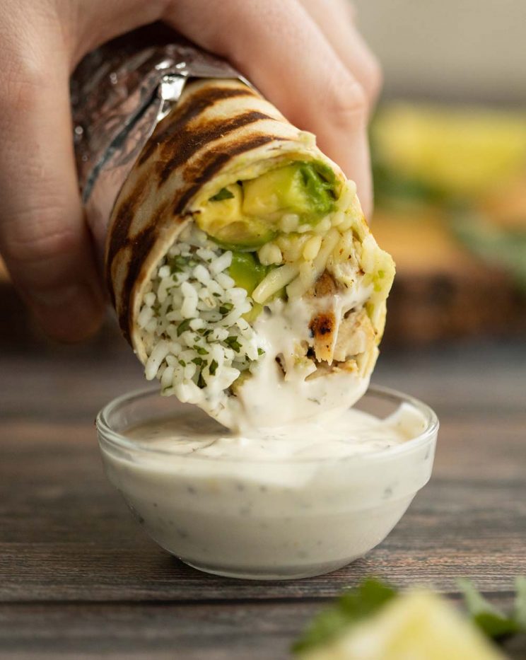 dunking a burrito into a small glass pot of ranch