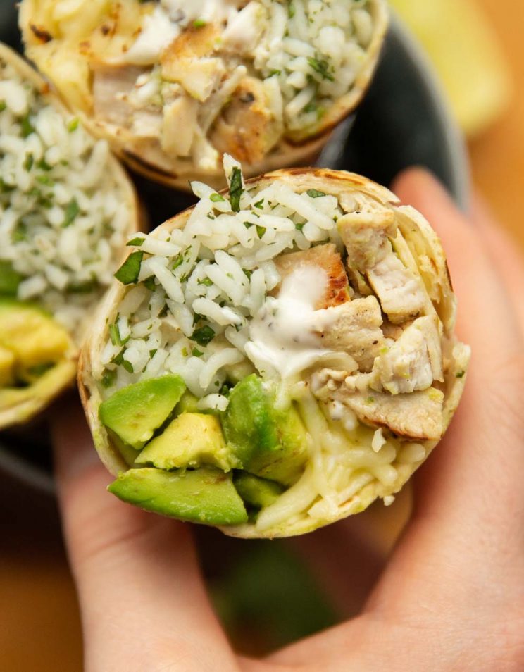 overhead shot of hand grabbing on to sliced open burrito