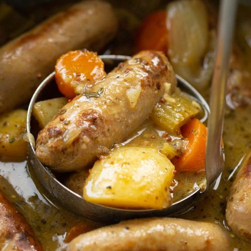 silver ladle in casserole scooping out sausage