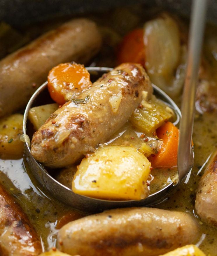 silver ladle in casserole scooping out sausage