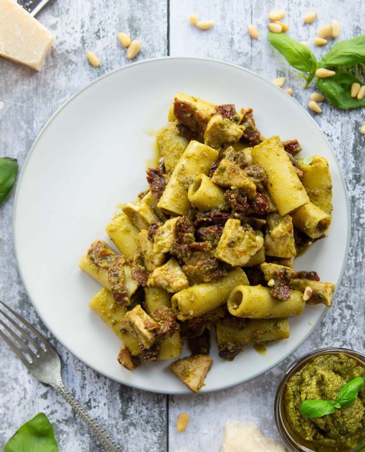 overhead shot of pasta on white plate surrounded by ingredients for garnish