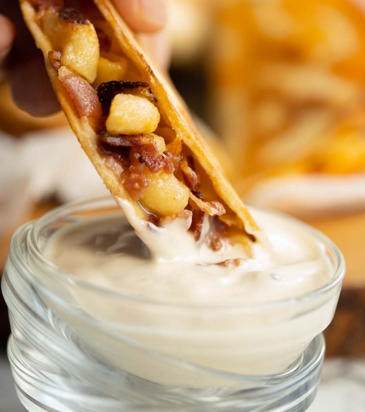 quesadilla dunking into dip in small glass pot