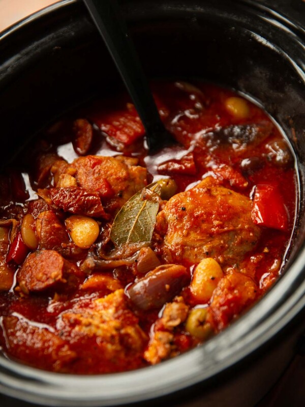 black serving spoon digging into slow cooker of chicken and chorizo