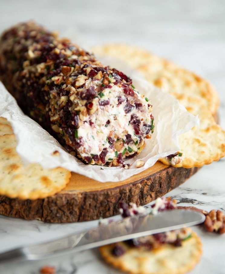 cheese log on wooden board surrounded by crackers