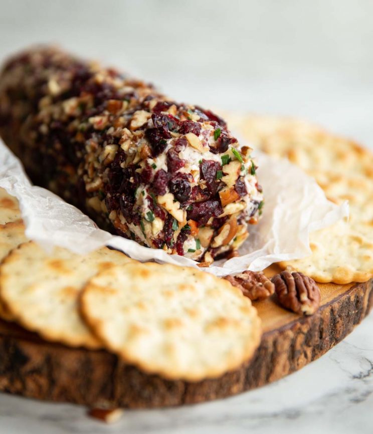 cheese log on wooden board surrounded by crackers