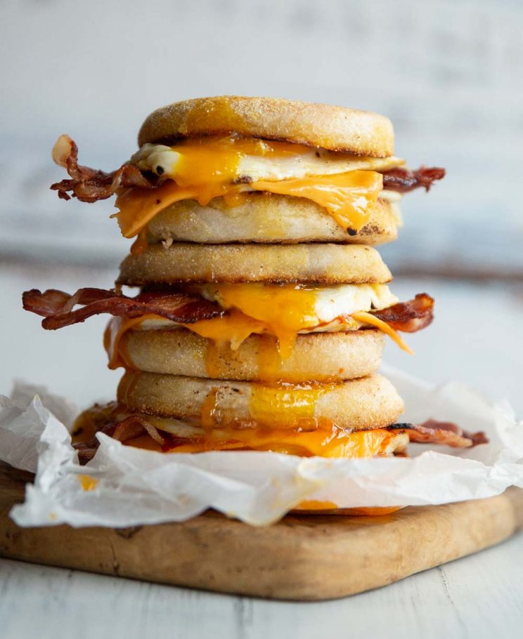 3 sandwiches stacked on each other on wooden board with yolk dripping out