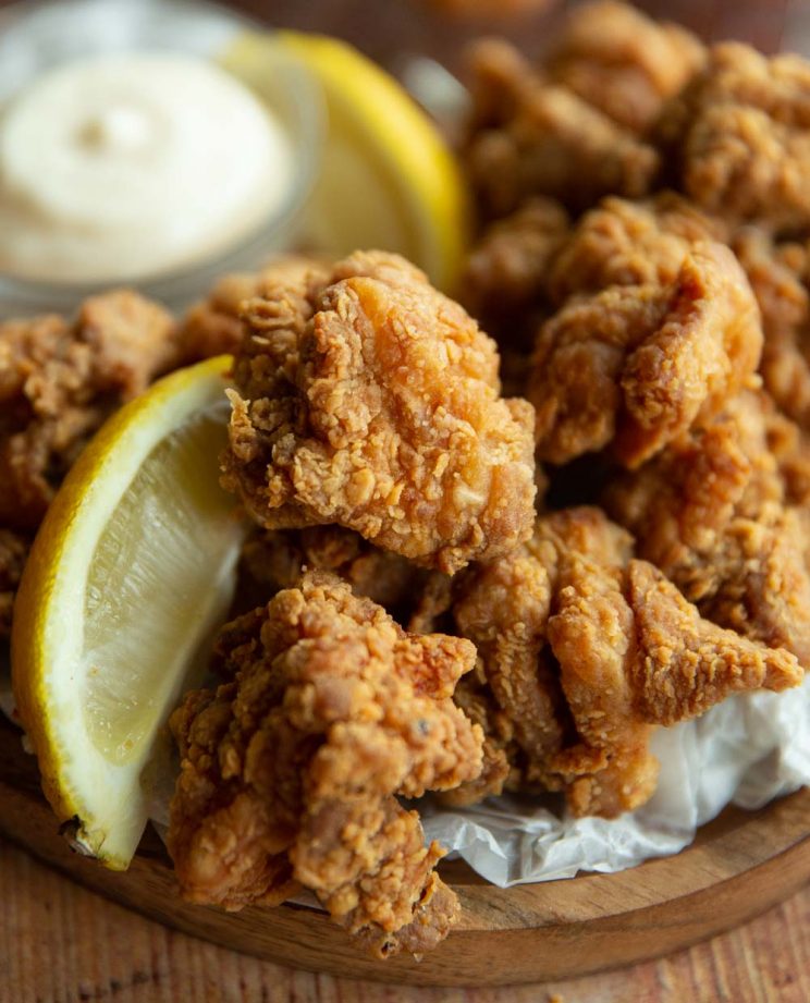 close up shot of chicken with lemon wedge on wooden board